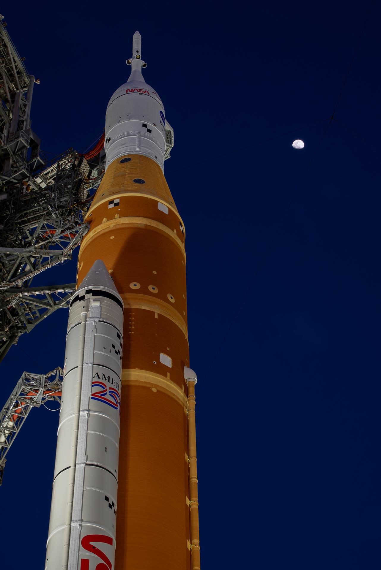 The Moon is seen shining over the SLS (Space Launch System) and Orion spacecraft, atop the mobile launcher on January 28, 2026. The rocket is currently at Launch Pad 39B at NASA’s Kennedy Space Center in Florida, as teams are preparing for a wet dress rehearsal to practice timelines and procedures for the launch of Artemis II.